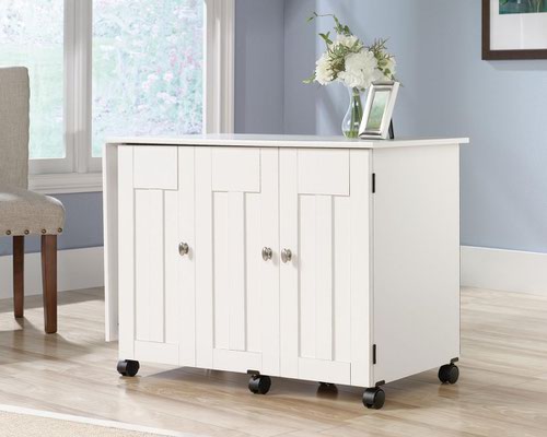 29294TK | The Teknik Office Sewing / Craft Cart in a Soft White Finish is the delightfully simple office furniture offering ideal for any office or room in the house. The generous melamine work surface provides ample space for all of your crafting activities and is highly resistant to heat, stains and scratches, it also extends out and is supported by the main doors using easy roll castors for ease of movement and additional working space. The storage behind these main doors includes two storage bins and a discreet hidden shelf for your sewing machine. There are also two adjustable shelves behind the smaller door for even more storage for your hobby or activity.