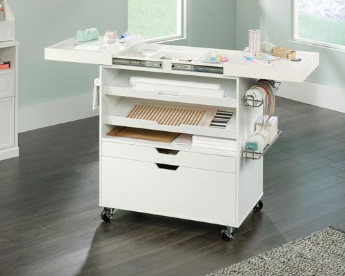 29259TK | The Teknik Office Craft Cart in a White Finish is the delightfully simple office furniture offering ideal for any office or room in the house. The generous work surface provides ample space for all of your crafting activities and it also slides out, revealing hidden divided storage for all miscellany of items. It has two height adjustable shelves which can be set at an inclined angle for easy access to craft paper. The two storage drawers with metal runners and the storage on the back of the cart is perfect for wrapping paper or fabrics. There are also metal baskets conveniently on the side of the cart to store or dispense ribbon or tape, what ever you need it for! The easy roll castors make it easy to move the cart where you need it.