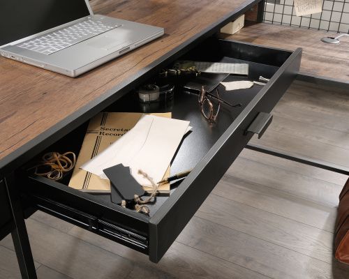 The Teknik Office Boulevard L-Shaped Desk is an ideal option for those that need the full office solution for their home office without taking up all the room! This fresh and modern styled desk benefits from a large desktop working surface finished in a stunning contrasting Vintage Oak Accent effect which not only provides more than ample space for writing and computer work, it is an ideal match for all decorative interiors. There are two storage drawers with full extension slides to stash all manner of desking stationery as well as an adjustable shelf discreetly hidden behind a metal door with a wire mesh front, all finished in sleek black. The elevated shelving is perfect for displaying or storing any relevant office accessories and the practical and the neat and practical mesh above the desk is ideal for clipping on reminders or creating an additional storage option space. There is also a grommet hole for discreet cable management. The look is completed with a beautifully finished powder coated metal frame, ensuring durability and life on the desk. This desk also benefits from a 360 degree finish, for effortless and versatile placement anywhere within your home or office working area.