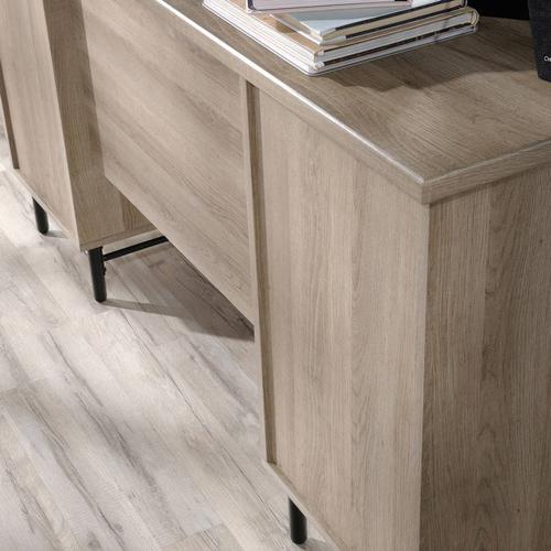 The Teknik Office Avon Leather Handled Desk is a charming and delightfully contrasting coloured option for all styles of office and colour schemes.  This fresh and modern styled desk benefits from a large desktop working surface in Sky Oak effect finish which provides more than ample space for writing and computer work. It also includes two file drawers with full extension slides for holding letter-size hanging files as well as four storage drawers featuring metal runners with safety stops in a beautiful contrasting white accent. The drawer fronts also feature an unusual yet stunning addition of drawer pulls in durable brown leather for an extra touch of class. The desk top has grommet holes for electrical cord access to ensure you can wire up your necessary hardware in a neat and orderly fashion. Beautifully finished with a powder coated metal base, this desk will blend effortlessly within your working area. This desk also benefits from a 360 degree finish, with the option to be freestanding. 