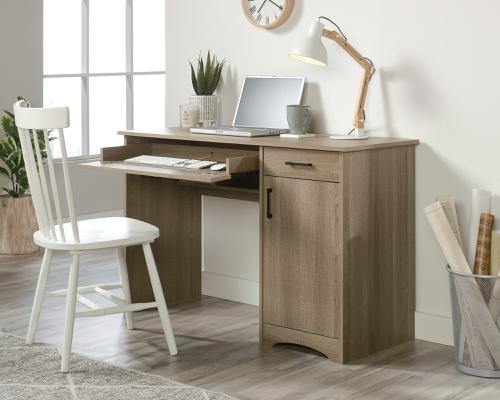The Teknik Office Essentials Computer Desk in Summer Oak is a fantastically functional option for the home, student and university halls where space is limited but computer work is utmost. This smart little desk offers a spacious top surface that provides you with the room you need for all your office essentials like your laptop, folders, collection of notepads and an accent lamp. This computer desk features a large drawer/shelf with a flip-down panel for your keyboard and mouse. The small storage drawer opens and closes on smooth metal runners for convenient storage for all your hidden stationery needs. This item also features a hidden storage area behind the door that includes an adjustable shelf and accommodates a vertical CPU tower. Other features includes a cord management system with pass-throughs for tidiness. The beautiful summer oak tone of this desk makes it an ideal match for all rooms and office colour schemes. 