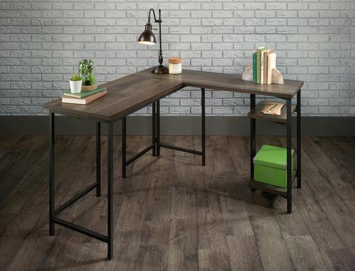 The Teknik Office Industrial Style L-Shaped Executive Desk is a sharp and minimalist design for those that need the full office solution for their home office without taking up all the room. It has a Smoked Oak effect finish desktop and shelves with a contrasting durable black metal frame which is ideal for all styles and colour schemes. The large lightweight yet strong desktop and return provides a generous working area for all manner of study and essential office work. This L-shaped desk features open storage with two fixed shelves which allows easy access to all of your office accessories. This also benefits from a 360 degree all round finish which means it can be freestanding anywhere within your home. All in all, a fabulous solution for all your home office needs.