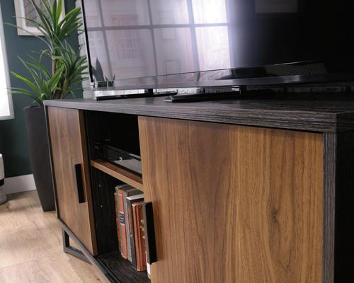 The Teknik Office Canyon Lane TV Stand in Brew Oak finish and Grand Walnut accents is the versatile and stylish choice for any living or working area. This item can accommodate up to a 60 inches and if you didn't wish to use it for this, it is versatile enough for use as a display unit or credenza, providing a perfect space for your living room displays, wine racks and your favourite houseplant or five!  This simple and modern TV Stand has three adjustable shelves for even more flexibility and two of these can be hidden behind sliding doors. The enclosed back cut-outs allow a convenient path for cables / cords and the black powder coated metal base ensures increased stability and durability.