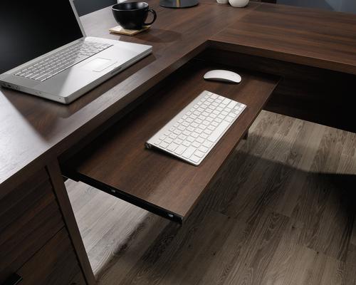 12767TK | The Teknik Office Elstree L-Shaped Desk is an ideal option for those that need the full office solution for their home office without taking up all the room! This louvre-style detailed desk has a large desktop and return working surface finished in a stunning spiced mahogany effect which not only provides more than ample space for writing and computer work, it is an ideal match for all decorative interiors. There are three storage drawers with metal runners and safety stops to stash all manner of desking stationery as well as an additional storage area with an adjustable shelf discreetly hidden behind a door which is a perfect size to hold a vertical CPU tower. This desk also benefits from a slide out keyboard/mouse shelf that can be fixed in three different positions as well as a lockable lower filer drawer which can hold your important letter or legal sized hanging files. . There is also a grommet hole for discreet cable management. This desk also benefits from a 360 degree finish, for effortless and versatile placement anywhere within your home or office working area.