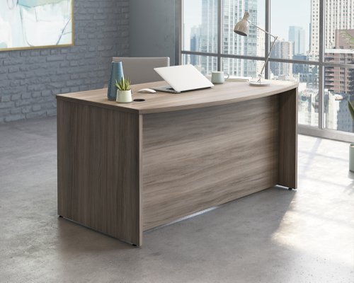 The Teknik Office Affiliate 1500 x 870 Bow Front Desk is our functional and commercial style option for all manner of colour schemes and work spaces.  This large attractively curved desk offers a very durable 1” thick melamine heat, stain and scratch resistant top to hold up your laptop, favourite beverage and display items with ease. It comes with two handy grommet holes for easy cord management and the adjustable base feet will ensure it stays perfectly level on even the most uneven floors.   The desk is also impact resistant with its high grade thermoplastic edges. Beautifully finished in a Hudson Elm effect, this Desk also benefits from a 360 degree finish for adaptable placement within your office. There are also other matching cupboards, desks, hutches and bookcases within the Affiliate range which will complement this item.