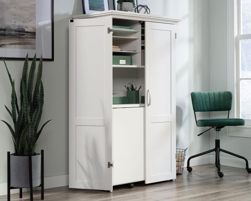 The Teknik Office Cotswold Hideaway Office / Craft Station in a Soft White finish is the delightfully simple office furniture offering ideal for any office or room in the house. The panelled double doors open up to reveal cubbyhole storage which six adjustable shelves, perfect for all of your hobby or office storage. There is a centre shelf which pulls down to create a table with drop leaf extension, this is a generous working area for any hobby or office work you can dream up! It also has a lower slide out shelf with metal runners and safety stops. There is also cord management to hide away any unsightly wires. This item also has a 360 degree all round finish, ideal for perfect placement within your workspace. Please note, the product comes with an American 6-Gang extension as it is made in the USA. If purchasing this product please discard this through your normal recycling and simply purchase a UK 6-Gang extension.