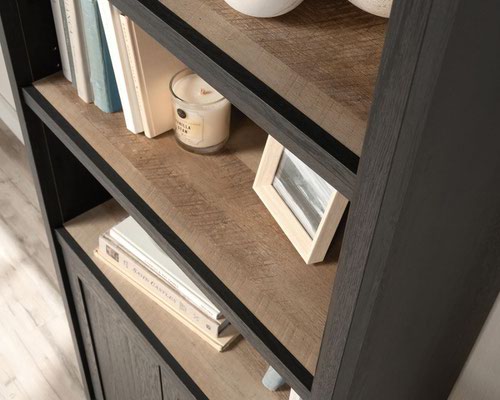 The Teknik Office Shaker Style Bookcase with Doors is a simple and clean looking style option, perfect for all colour schemes and decor.  Beautifully finished in a Raven Oak effect finish with contrasting Lintel Oak coloured accents, this simple and clean styled space saving storage option provides a convenient solution for those with limited space, simple and versatile to mount anywhere within your home. This item has three adjustable shelves for flexible storage, great for displaying your ornaments, favourite photo frames or essential reading materials. There is also hidden storage and a shelf behind double doors to discreetly stow the remainder of your library or office accessories. All in all, an ideal option to complement your living room and still keep within the style of your home. This bookcase is part of our Shaker Style range which includes a matching L-Shaped Desk and rectangular Desk.